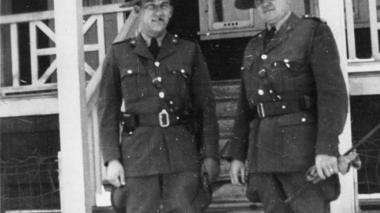 Two uniformed military officers standing outside a building on a snowy day.