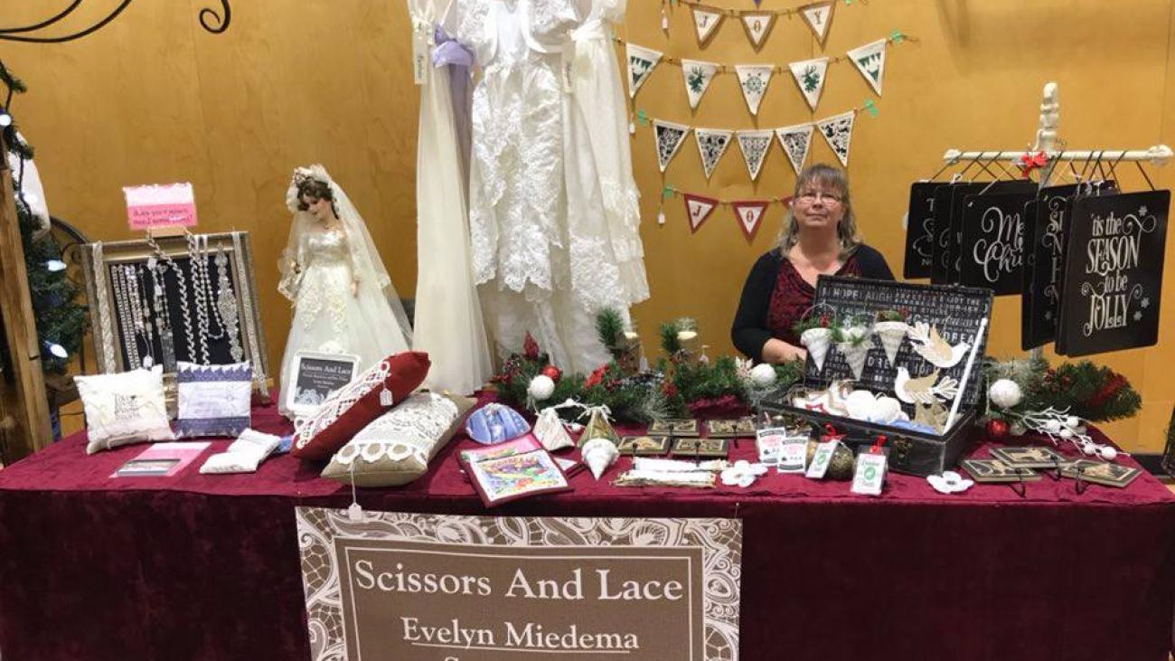 Sewing booth with dresses, accessories, and a woman sitting behind a table.