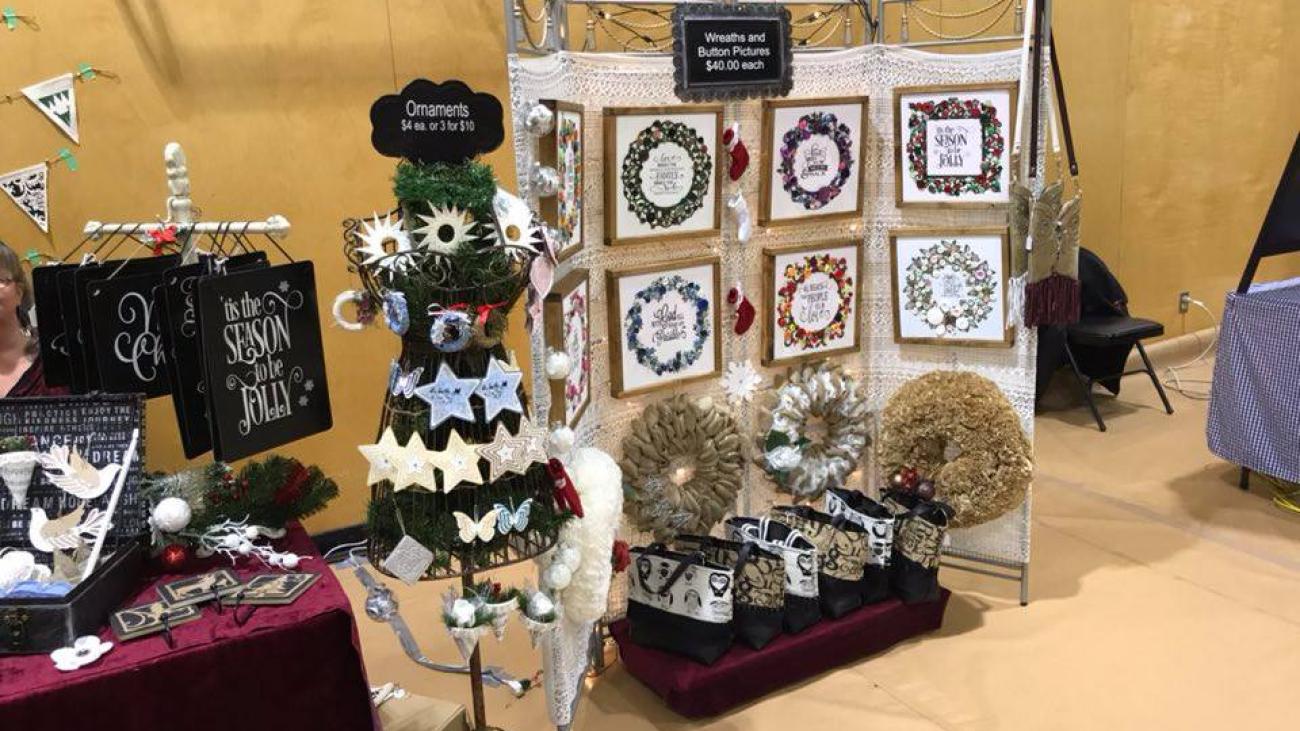 Craft fair booth with handmade wreaths and festive decorations displayed.