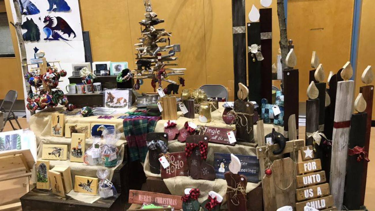 Craft fair booth with handmade wooden decorations and artworks displayed.