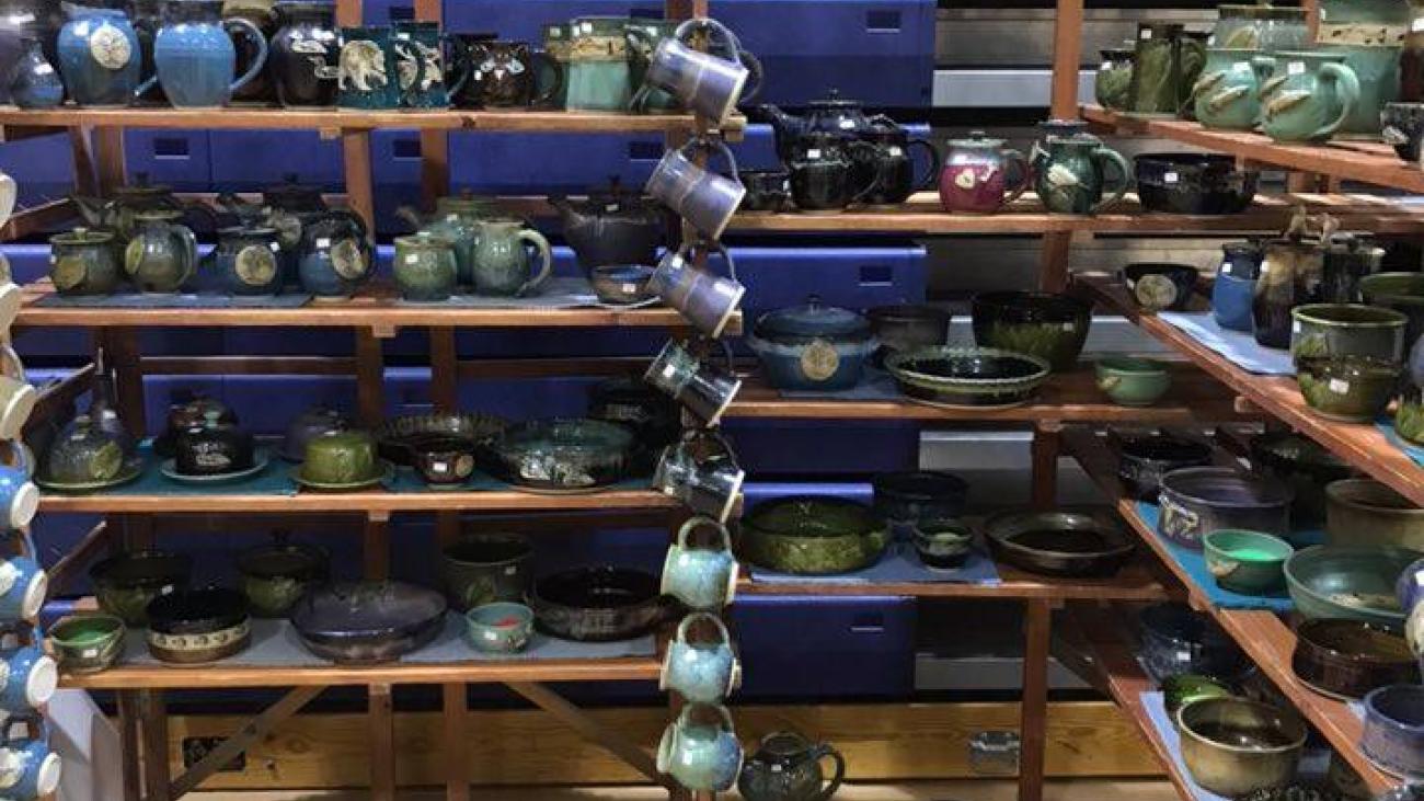 Pottery display on wooden shelves, featuring colourful bowls and plates.