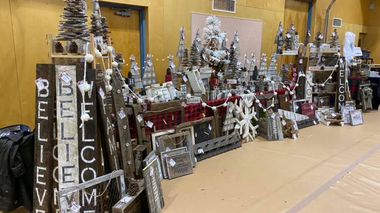 Festive decorations arranged in a gym, including trees and signs reading "BELIEVE" and "WELCOME".
