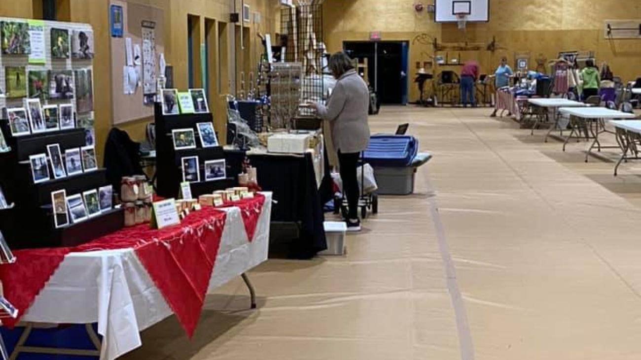 Craft fair in a gymnasium with tables and displays.