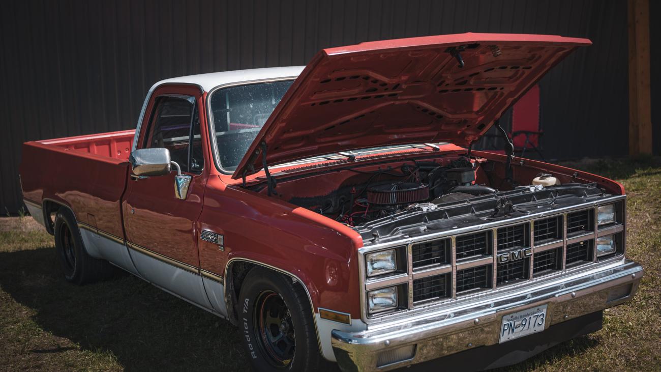 Red and white vintage pickup truck with the hood open.