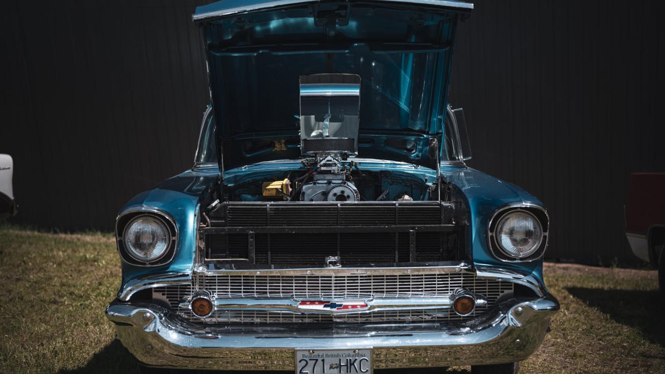 Classic blue car with hood open, showing engine details.