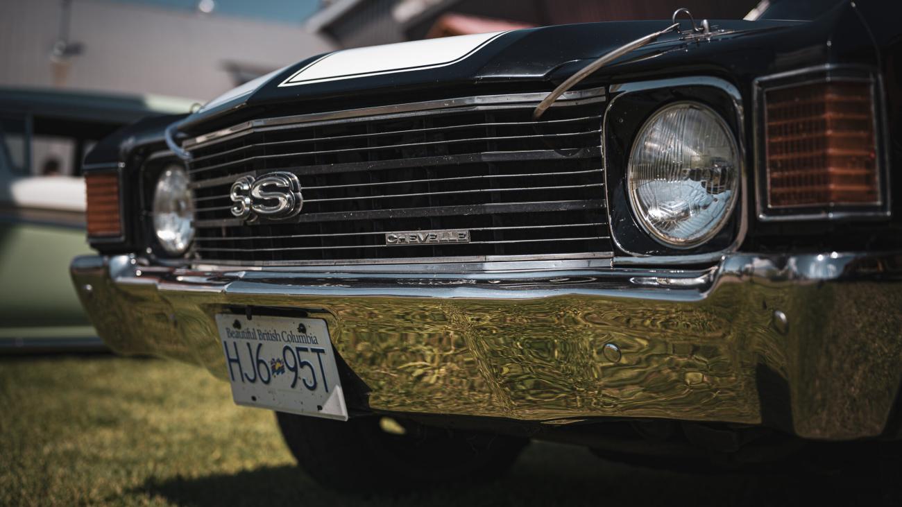 Classic black car with chrome bumper parked on grass.