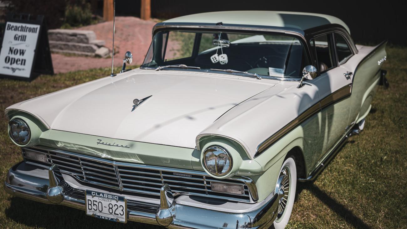 Vintage white and mint green car parked on grass.