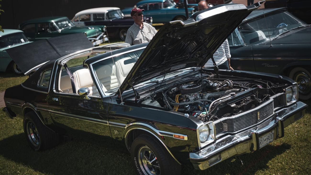 Classic car with hood open at outdoor auto show.