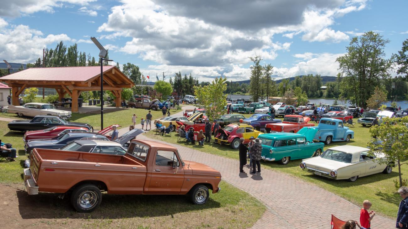 Classic cars displayed in a park under a cloudy sky.