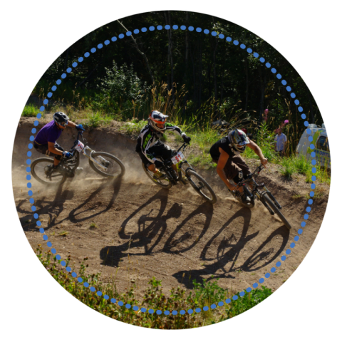 Three cyclists racing on a dirt trail in a forested area.