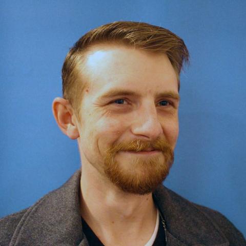 Smiling man with a beard against a blue background.