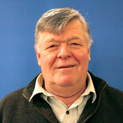 Smiling older man against a blue background.