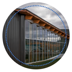 Modern building with large glass windows and wooden roof, under a cloudy sky.